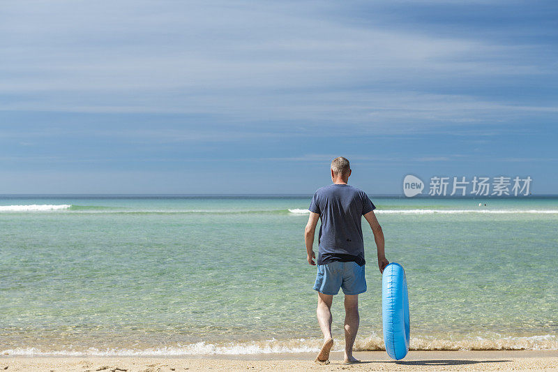 康沃尔Pedn Vounder海滩，一名男子戴着橡胶圈走向海边